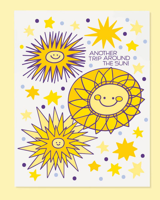 A greeting card with a colorful illustration of smiling suns and stars with the phrase 'ANOTHER TRIP AROUND THE SUN'.